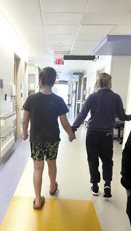 A boy and a nurse walk down the corridor of Boston Children's Hospital