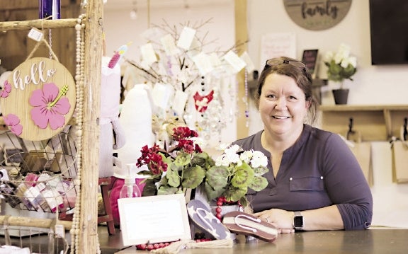 A woman smiles amongst vintage goods and a plant