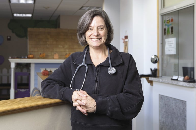 A photo of a female doctor wearing a black sweater and a stethoscope