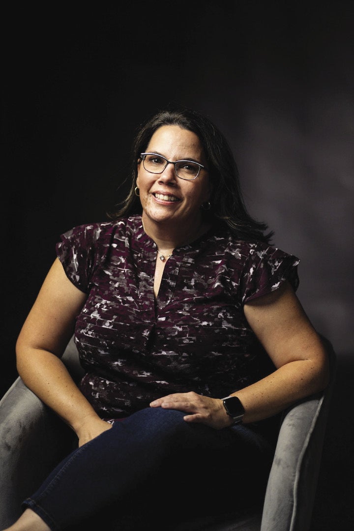 A woman sits in a chair for a portrait photo