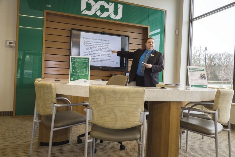 A bank employee inside a branch points at a screen