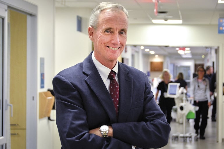 A man in a suit and tie smiles at the camera.