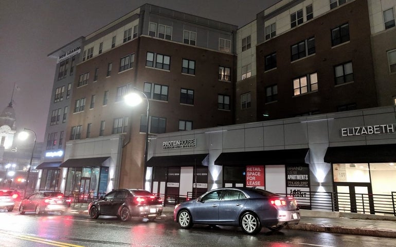 a five-story mixed use building with a street and cars in front.