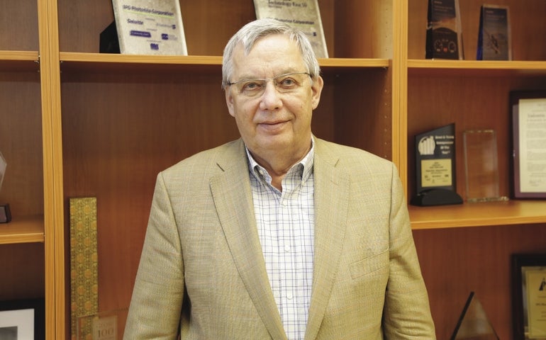 A man in a beige suit and glasses