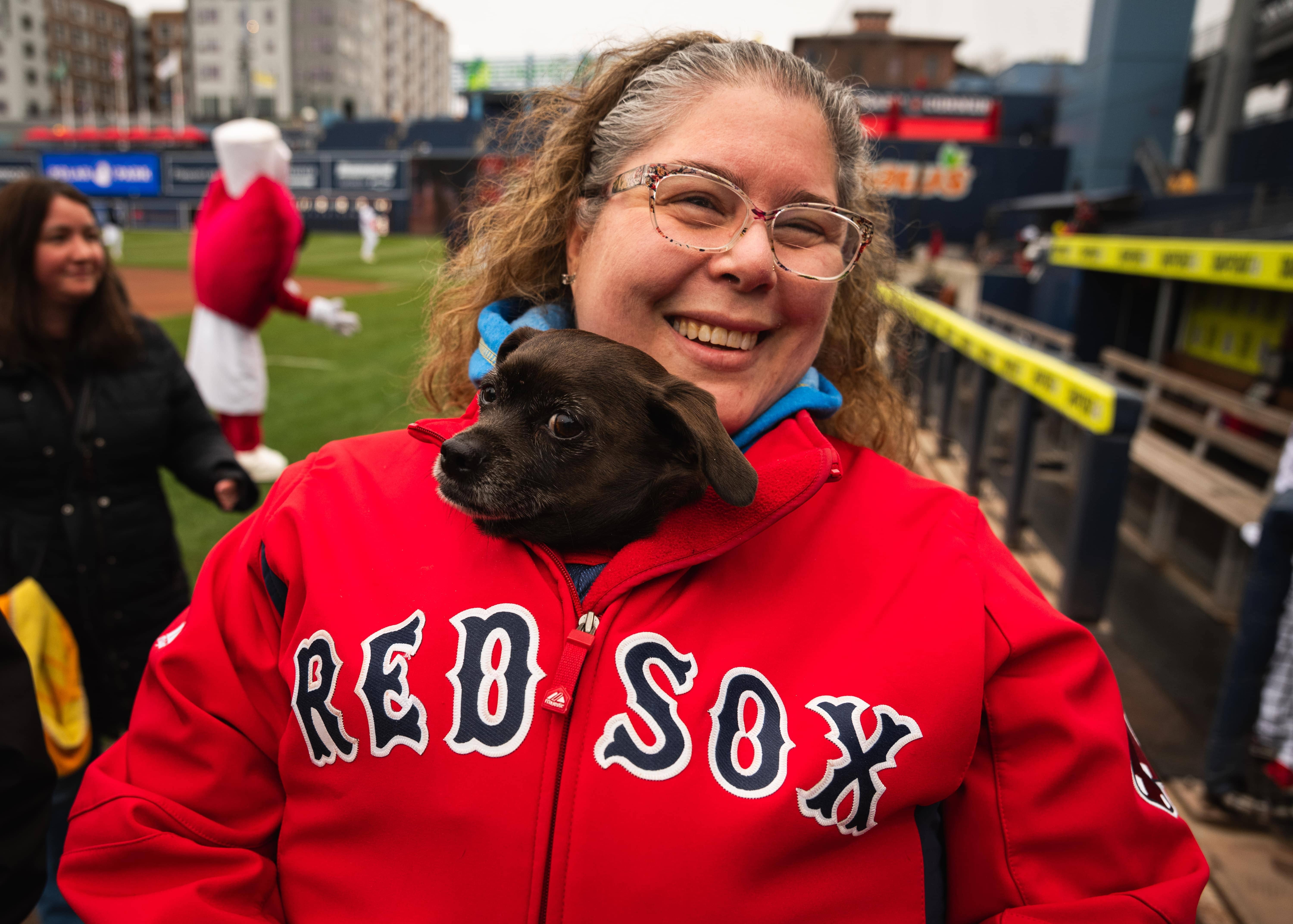 A small puppy sits in a woman's jacket