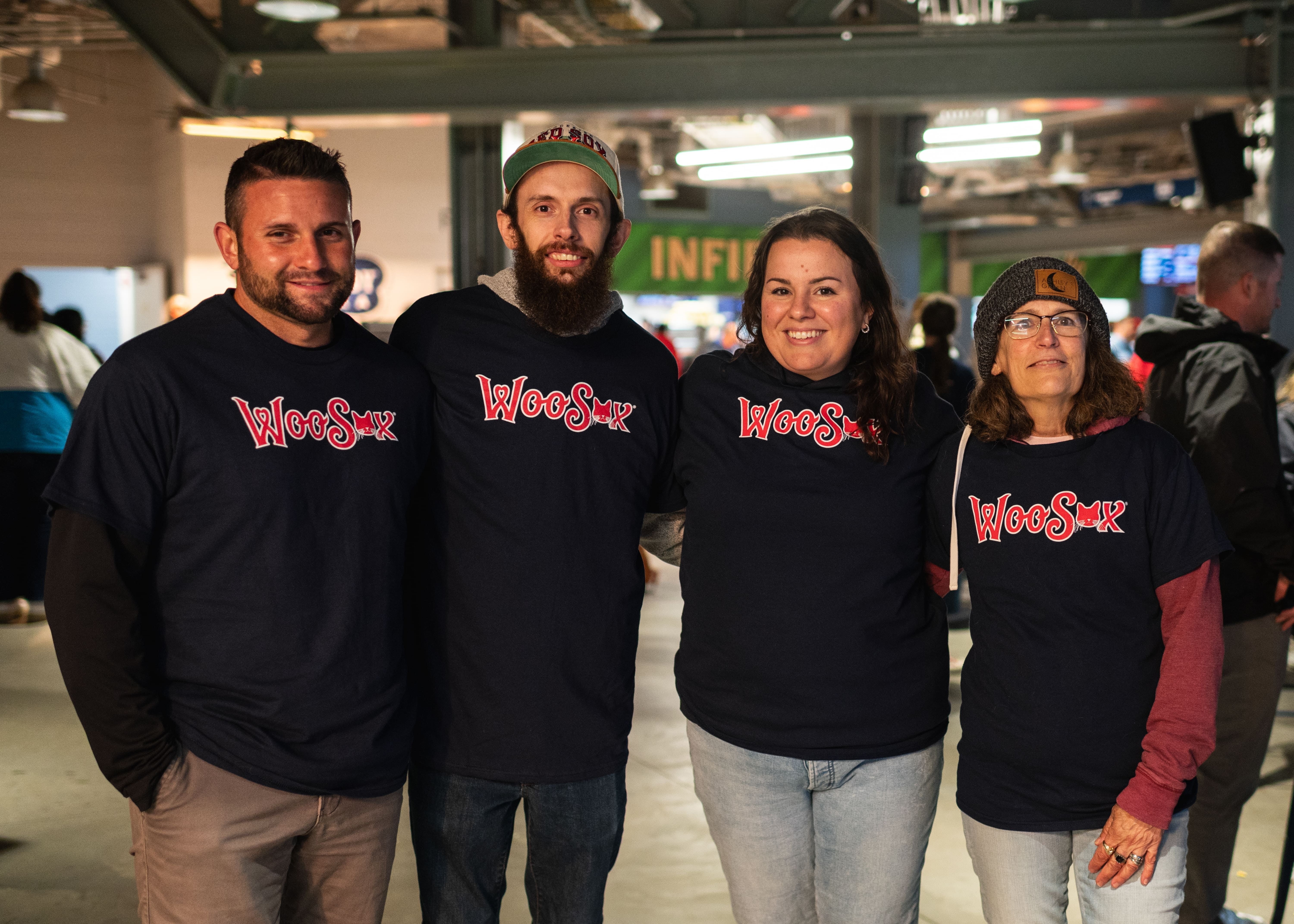 Four people wearing WooSox shirt where the third O in WooSox is a cat's face