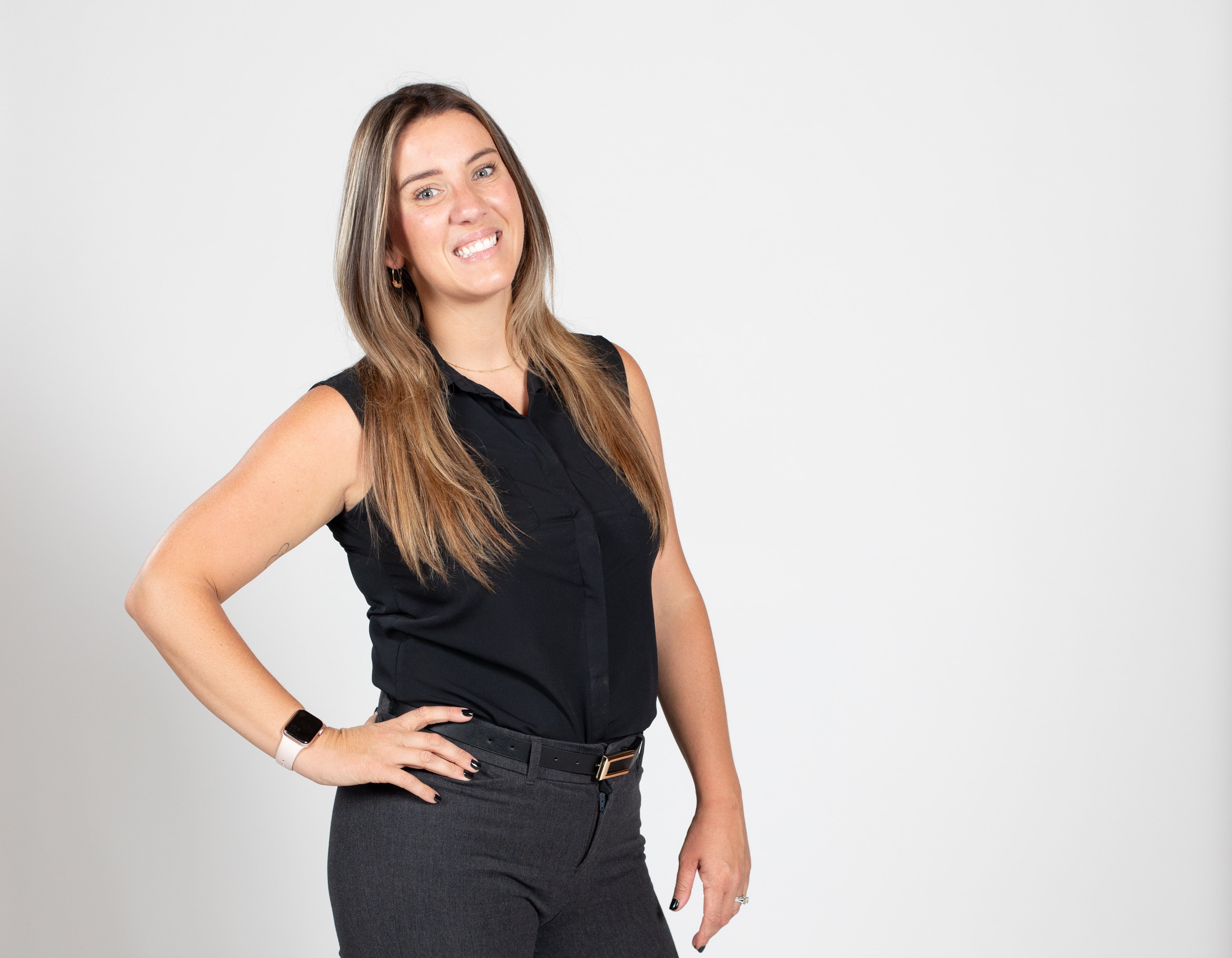 A woman wears a black top with gray pants.
