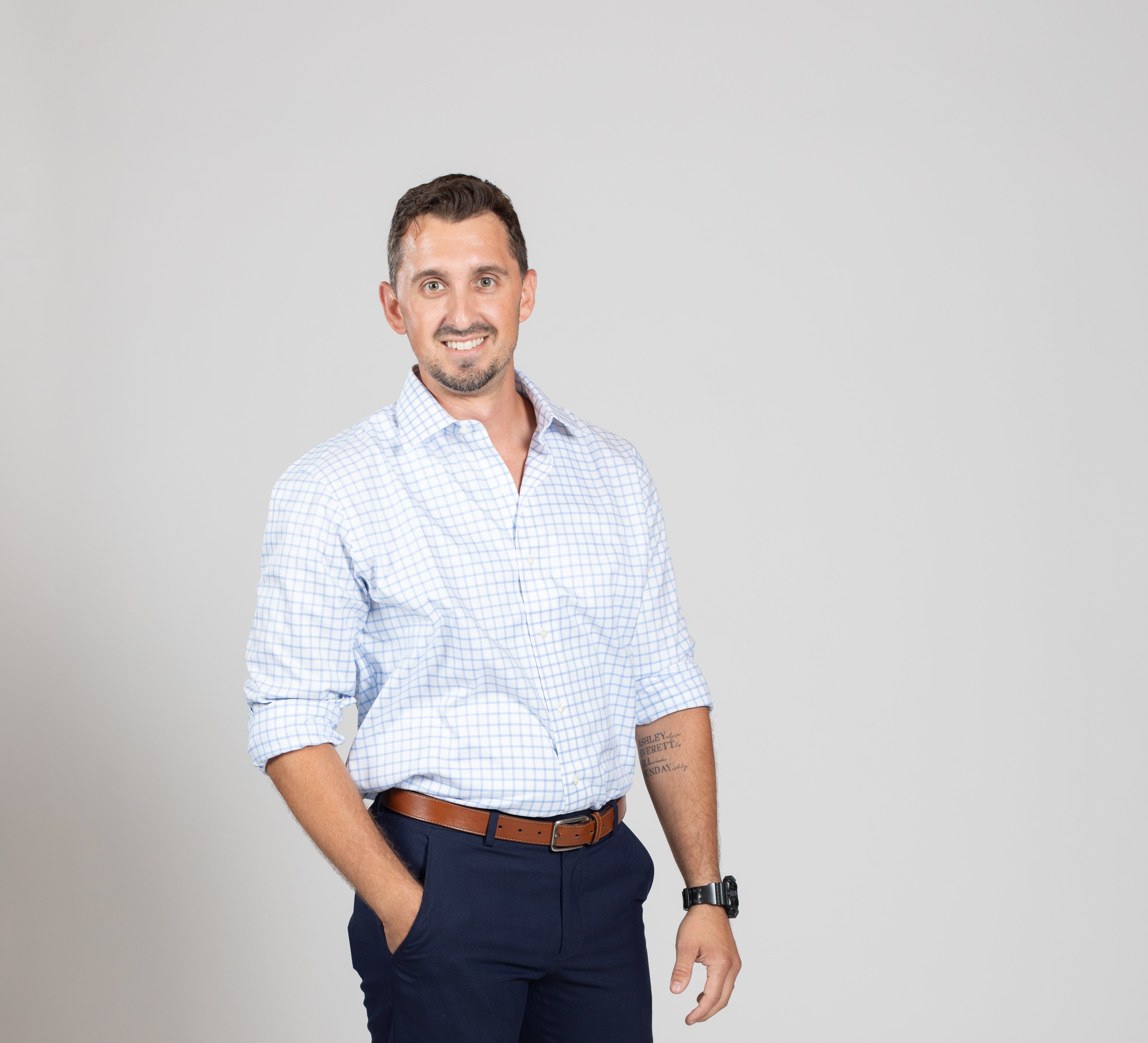Man in dress clothes points at camera with both hands while smiling