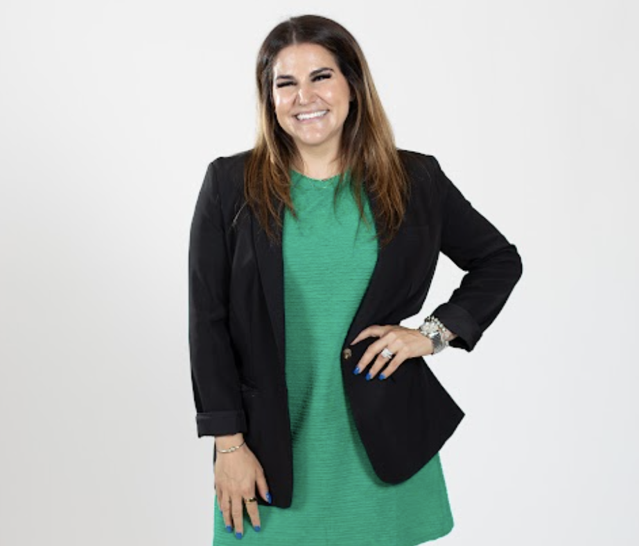 A woman wears a green dress and a black blazer.