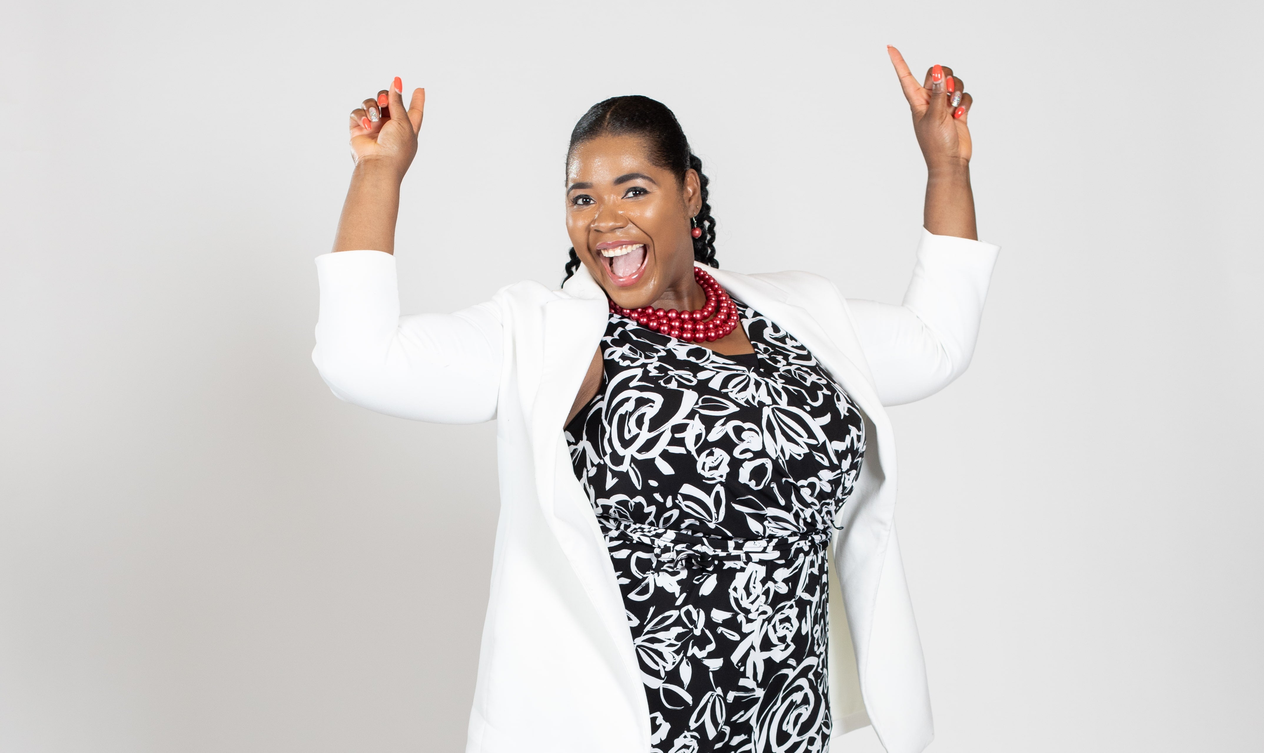 A woman wears a white jacket over a black flower-print dress.