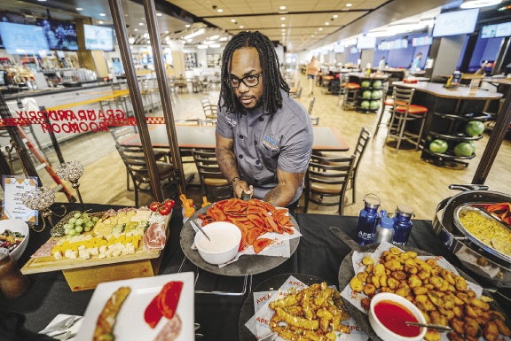 A man hold a platter of food over a buffet table full of food