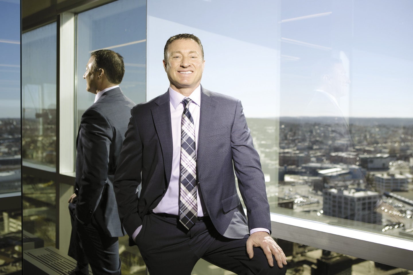 A man in a suit and tie smiles at the camera, with the Worcester skyline in the background.