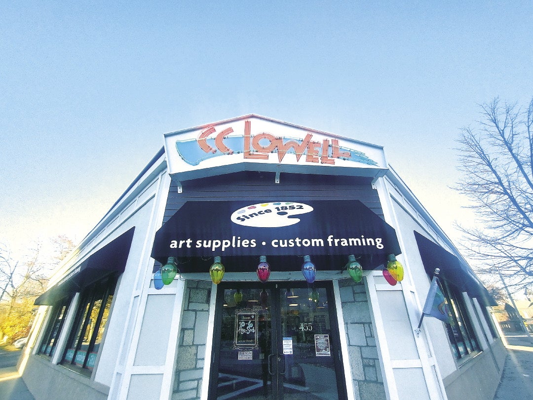 The entrance of a corner retail shop with signage and an awning above the door