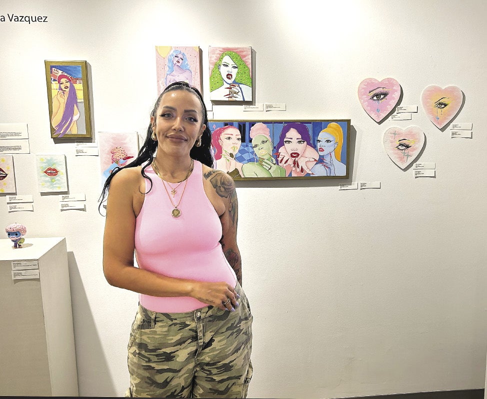 Woman in pink shirt and camo pants stands in art gallery
